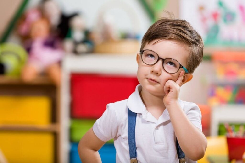 a young body ponder his behavior in a calm corner of his classroom where he is sitting at a table with drawers of activities to do behind him