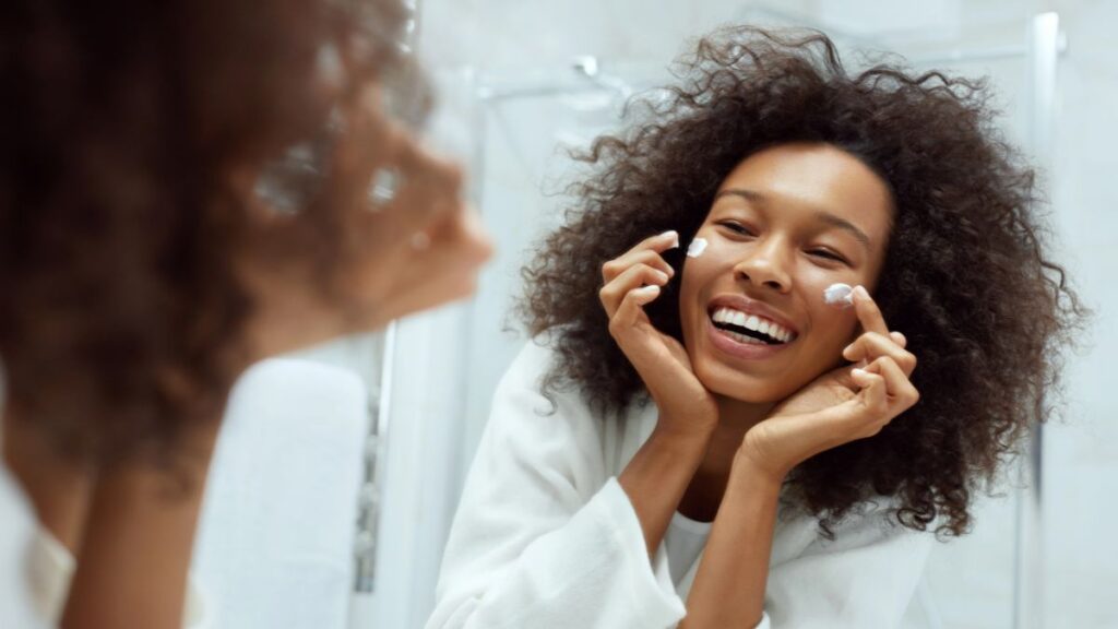 happy woman using face cream in mirror