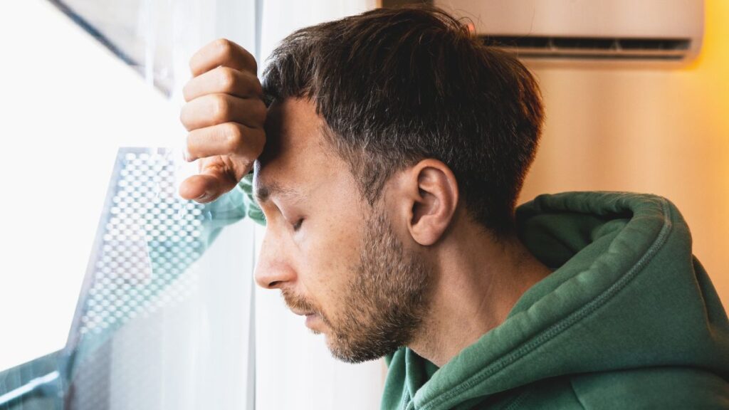 man leaning on window looking upset