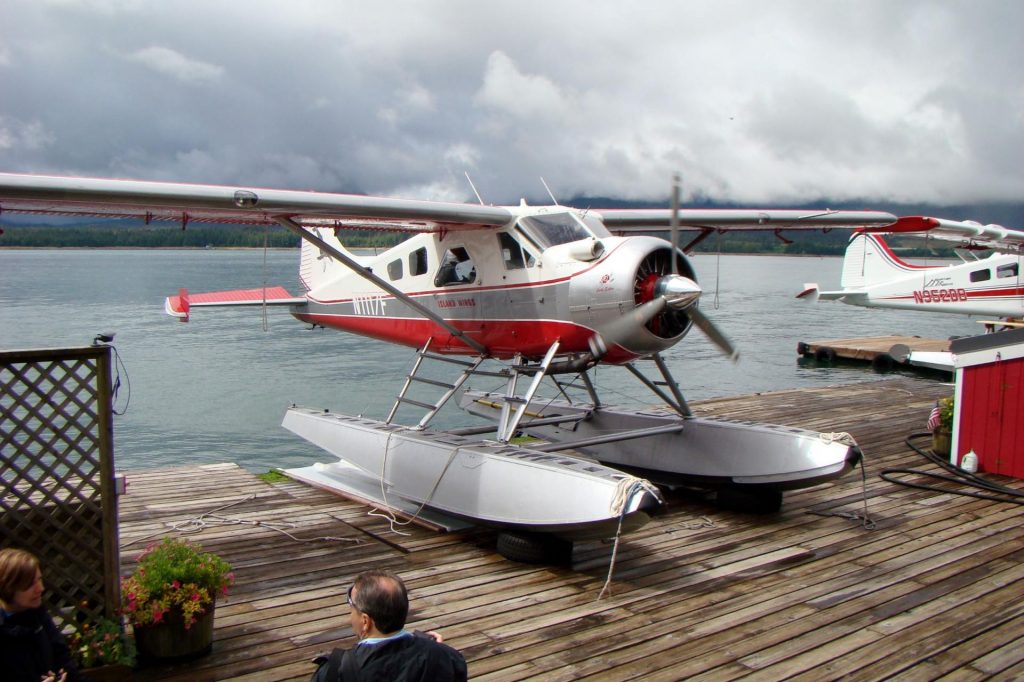 alaskan float plane red and white sitting on a platform ready to load riders