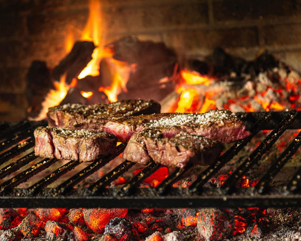 meat cooking in an open flame bbq pit