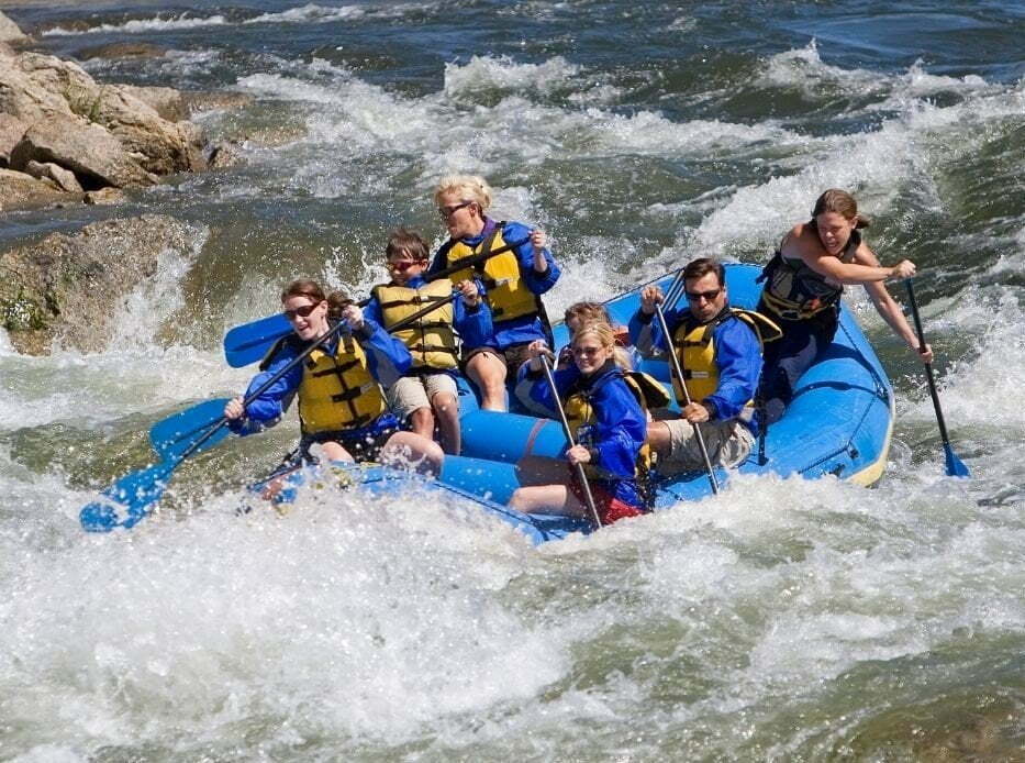 people white water rafting in a large blue raft