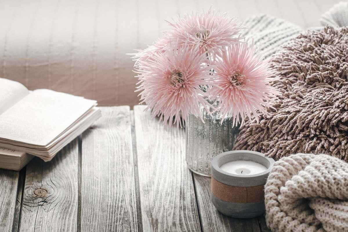 pale pink flowers candle and a book sitting on a wooden table