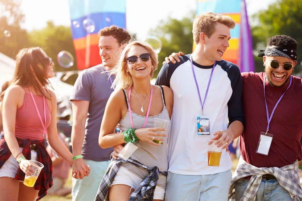 two young women and three young men having fun at a festival celebrating together