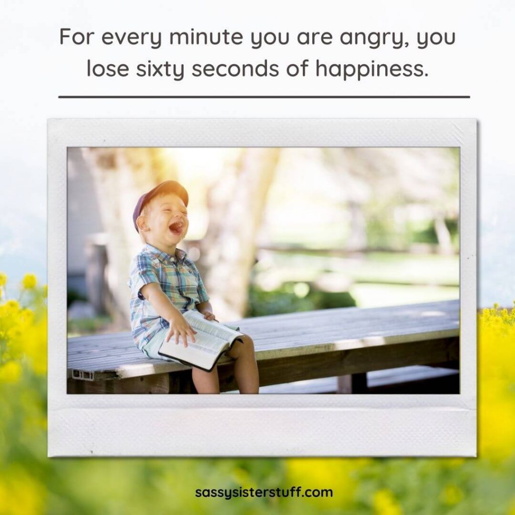 little boy sits on a picnic table laughing happily and a quote about happiness