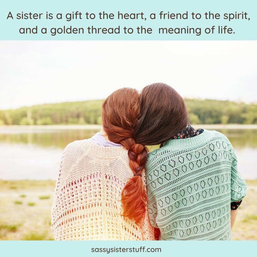 two women sitting on waters edge with their pigtails intertwined behind them