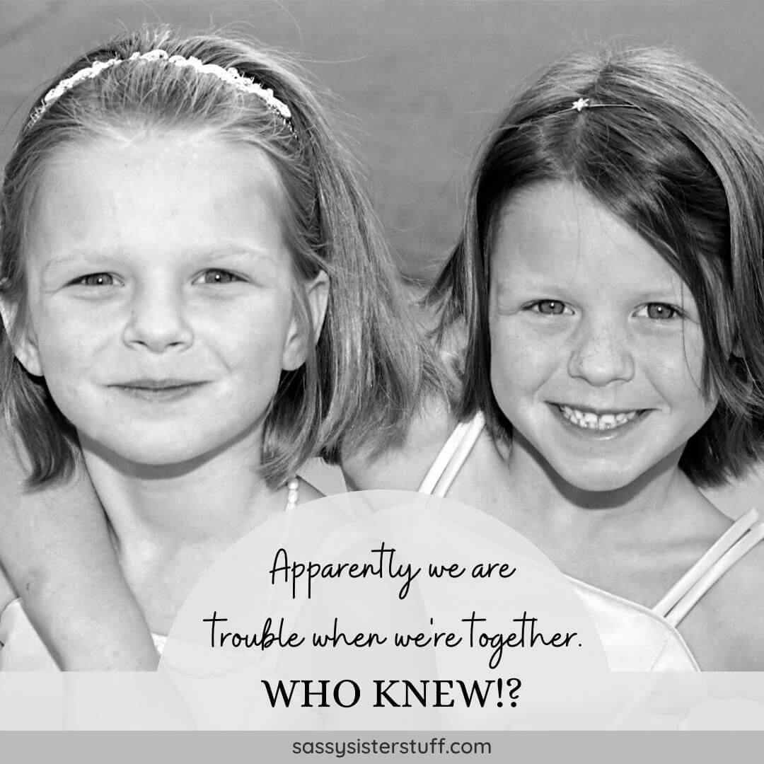 black and white photo of two little girls smiling and hugging with a funny sister quote