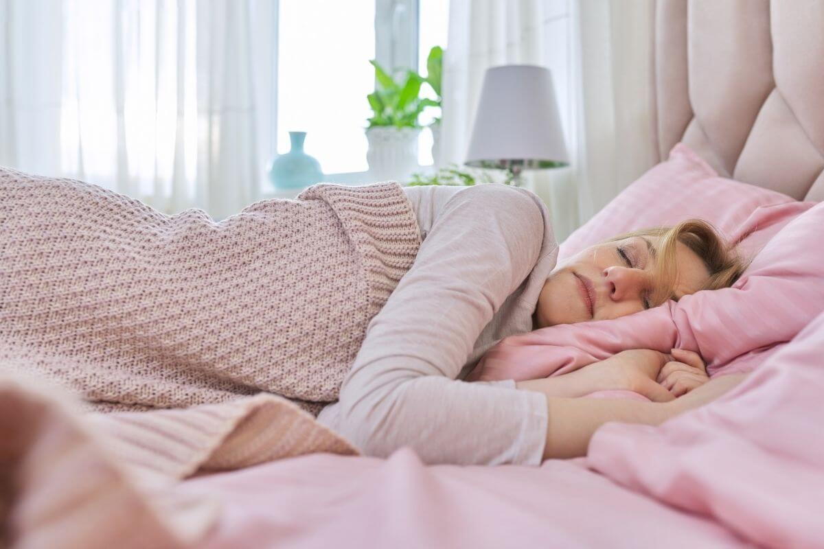 woman sleeping with green plants a lamp and a vase in the background