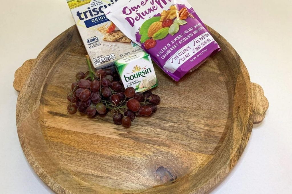 large round wooden charcuterie board grapes crackers cheese trail mix