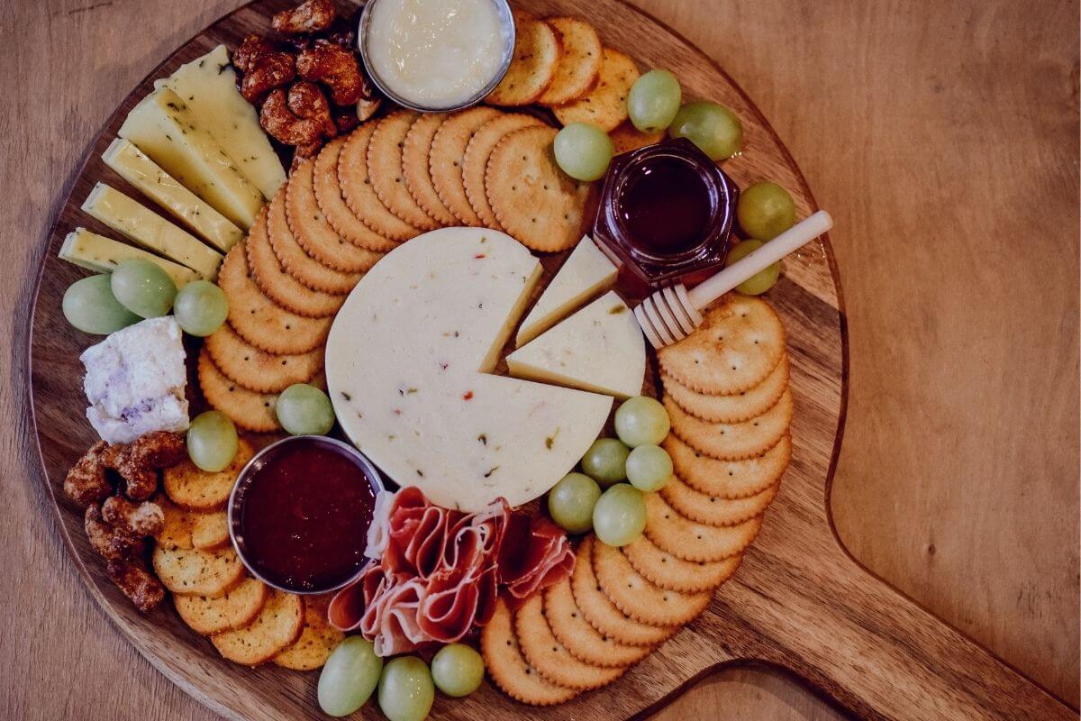 round wooden charcuterie board with handle cheese crackers fruits and dips