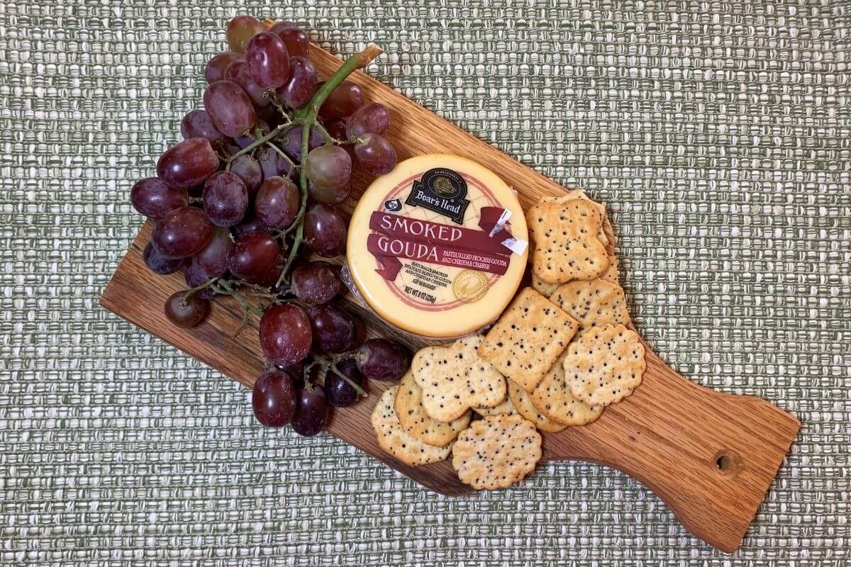 wooden cutting board type charcuterie with grapes cheese crackers