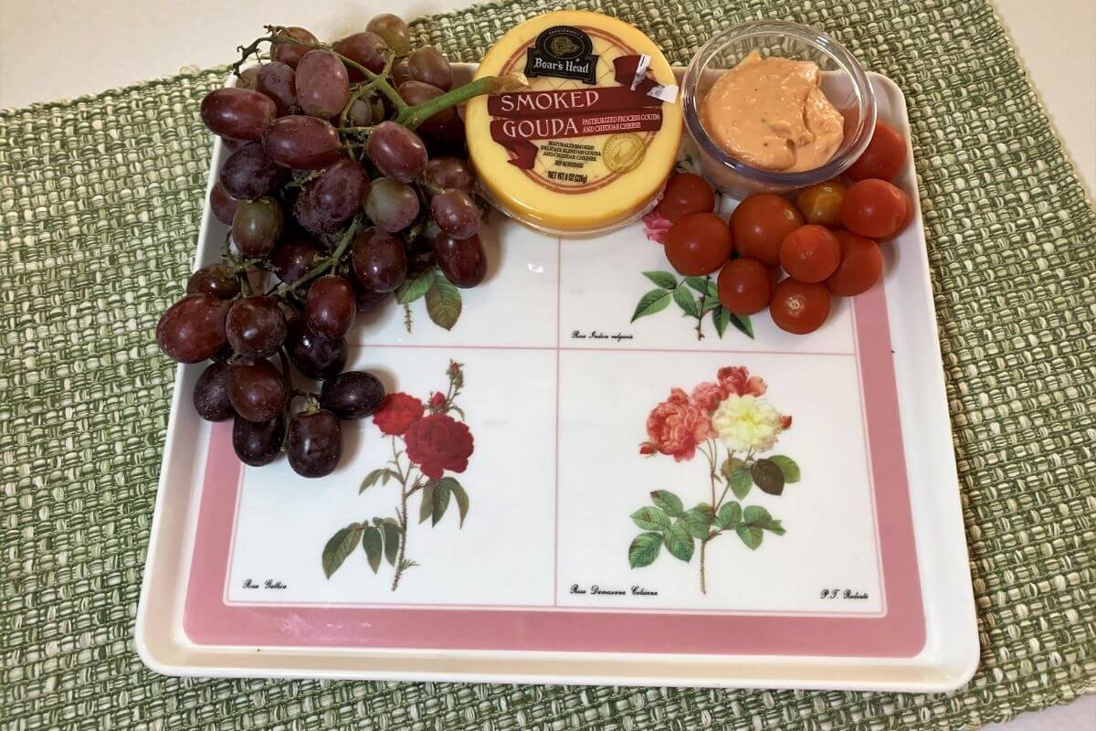 pink and white floral platter with grapes cheese cherry tomatoes and dip