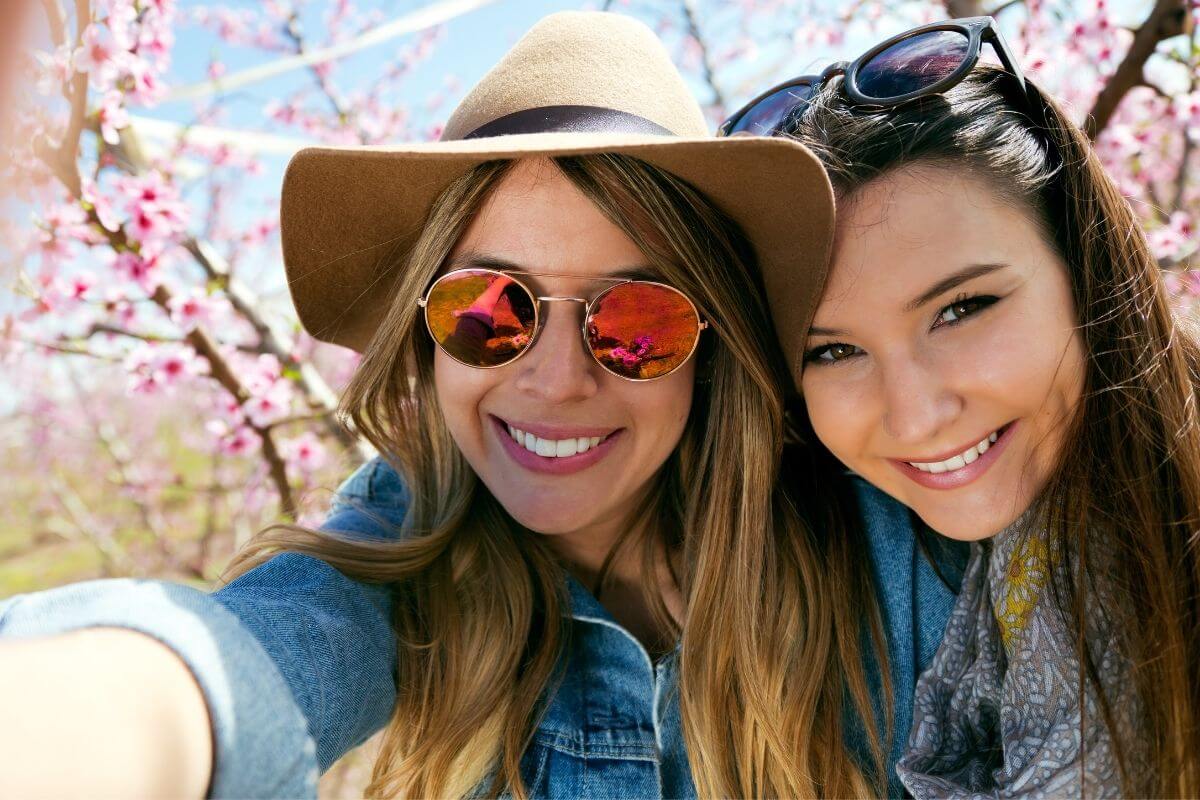 two happy young ladies head to head take a selfie