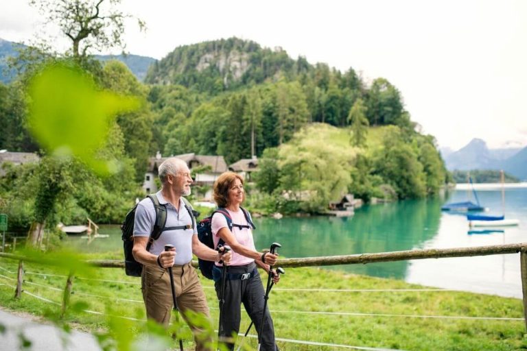 happy man and woman hike along the edge of a lake in the mountains