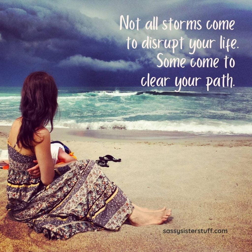 a woman sits on a beach with a storm in the distance and an inspirational quote