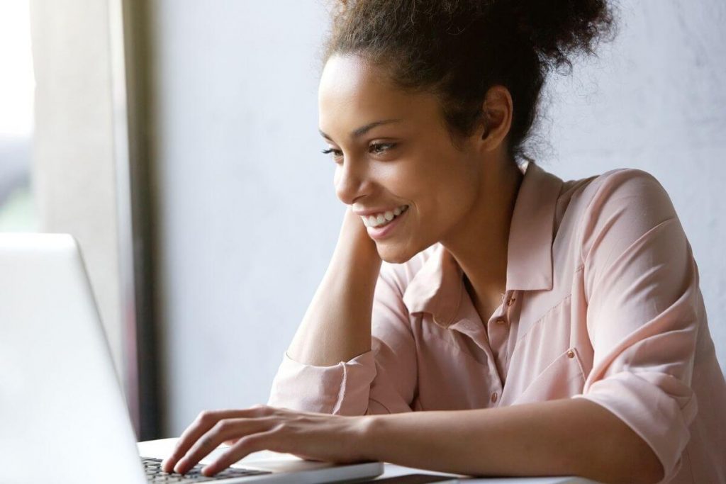 happy woman looking at laptop for best websites or self improvement