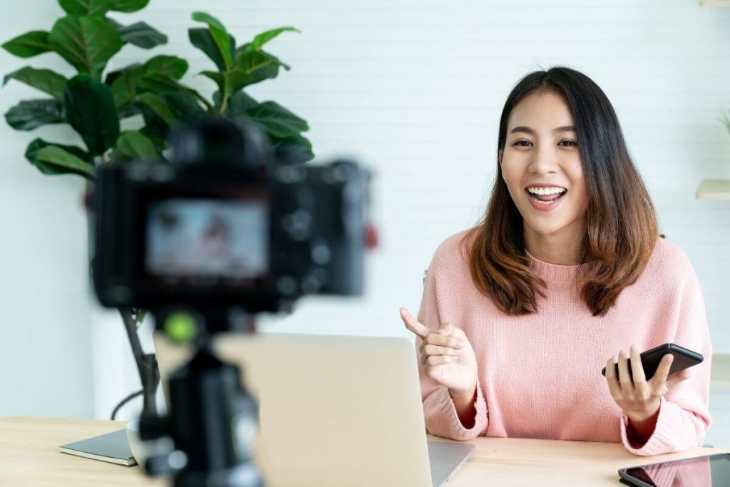 happy woman looking at laptop and camera while working on self improvement