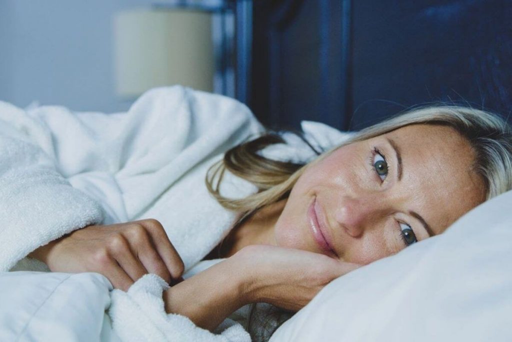 a women snuggles in bed resting for good health