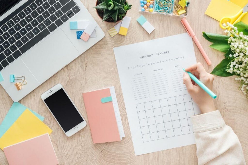 desktop with supplies and woman working on self improvement tasks