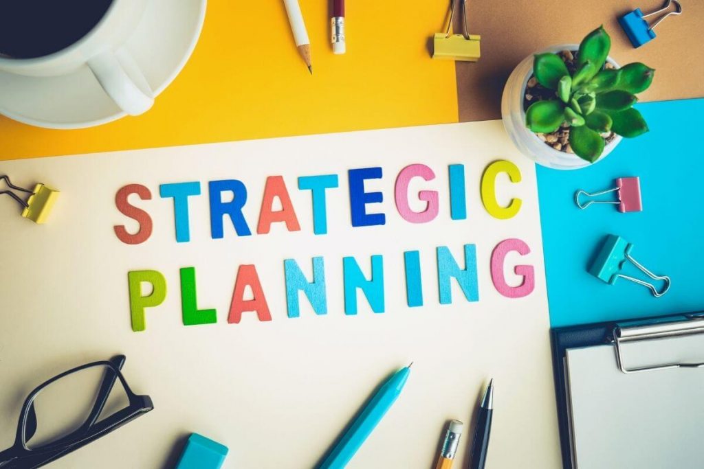 bright papers and desk supplies laying on a desk with strategic planning spelled out in different colored stickers