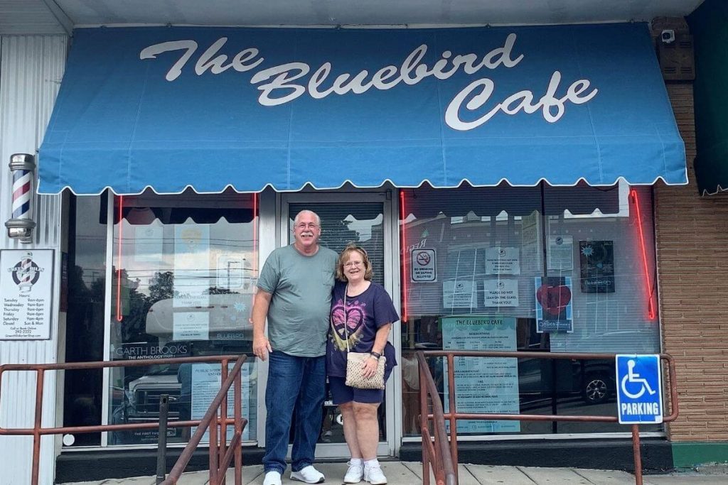 happy tourists stand in front of the Bluebird Cafe in Nashville