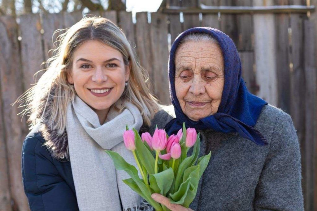 younger and older woman holding a bouquet of flowers with a heart of gratitude