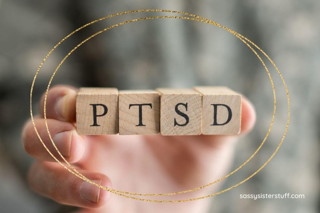 a hand holds up four wooden blocks that spells out PTSD