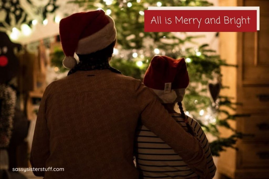 a parent and child sitting in a dark room look at a beautiful Christmas tree after getting organized for the holidays and relaxing together