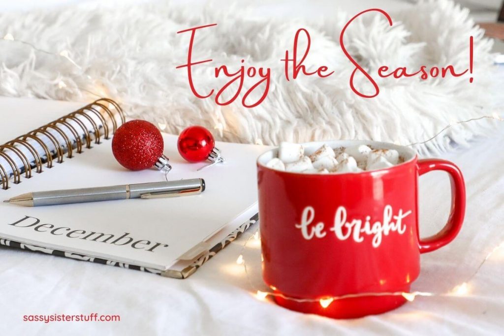 a December journal and pen with hot chocolate in a red mug that says be bright and red letters saying enjoy the season