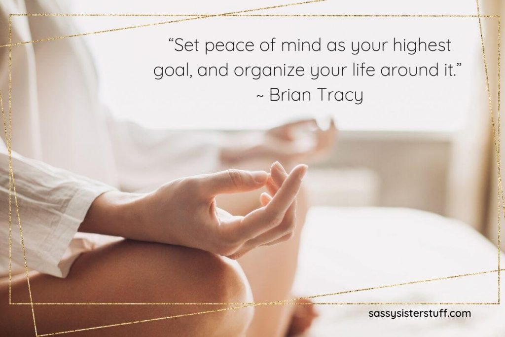 woman sitting on a bed doing yoga with a quote about organizing your life around your peace of mind