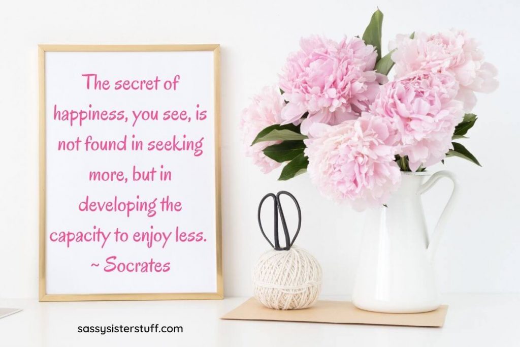 beautiful pink peonies in a white pitcher vase with a framed quote about happiness and simplicity from Socrates