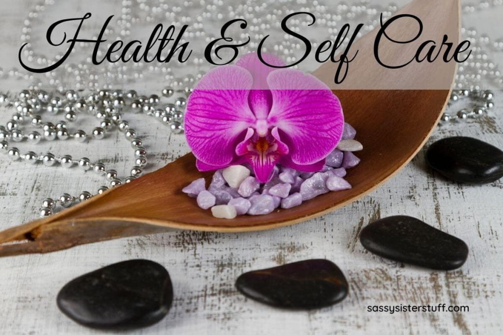 healing stones, crystals, and a flower with silver beads laying on a table showing the health and self care aspects of a balanced life