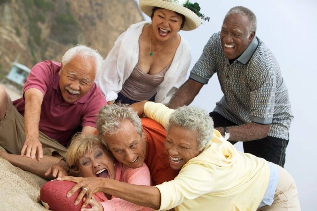 six middle aged men and women have fun socializing and tossing a football around to maintain their intellectual wellness