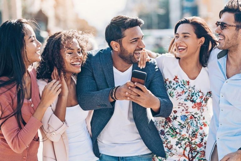 a group of five friends walking together laughing and showing how to improve social wellness