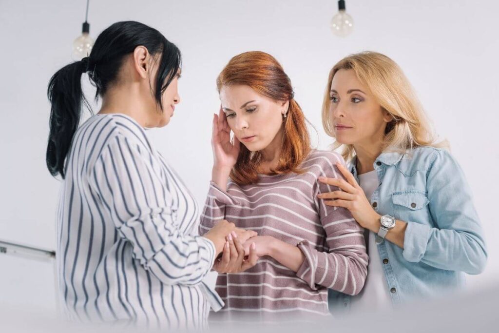 three young and middle aged women seem to comfort each other because one of them seems to be addicted to stress