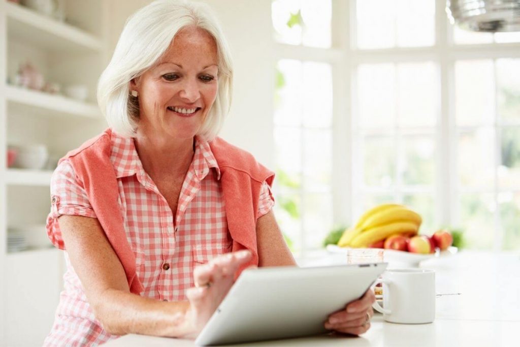 middle aged smiling woman wearing a beautiful coral top uses a table to show for online boutique clothes women love