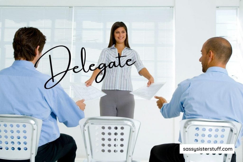 a young woman hands papers to two men and the word delegate to represent business skills that can help improve your personal life