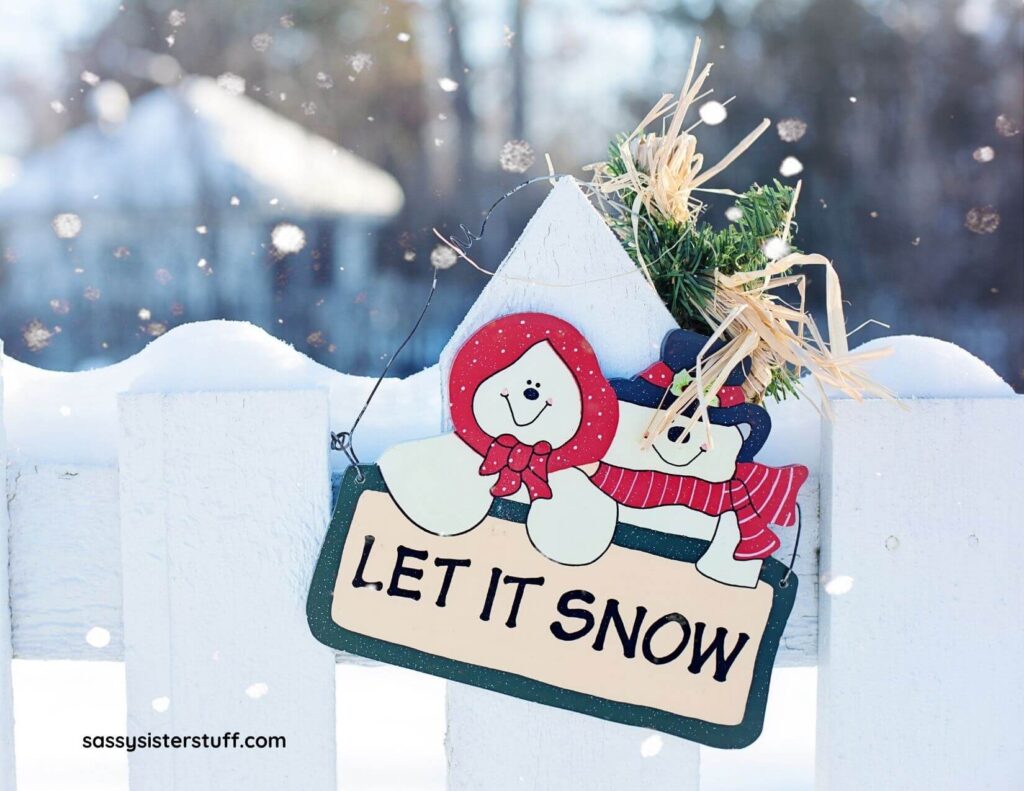 white wooden fence with a let it snow sign that has mr and mrs snowman on it