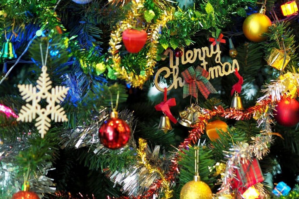 close up image of a christmas tree with bright ornaments in red yellow blue green and gold