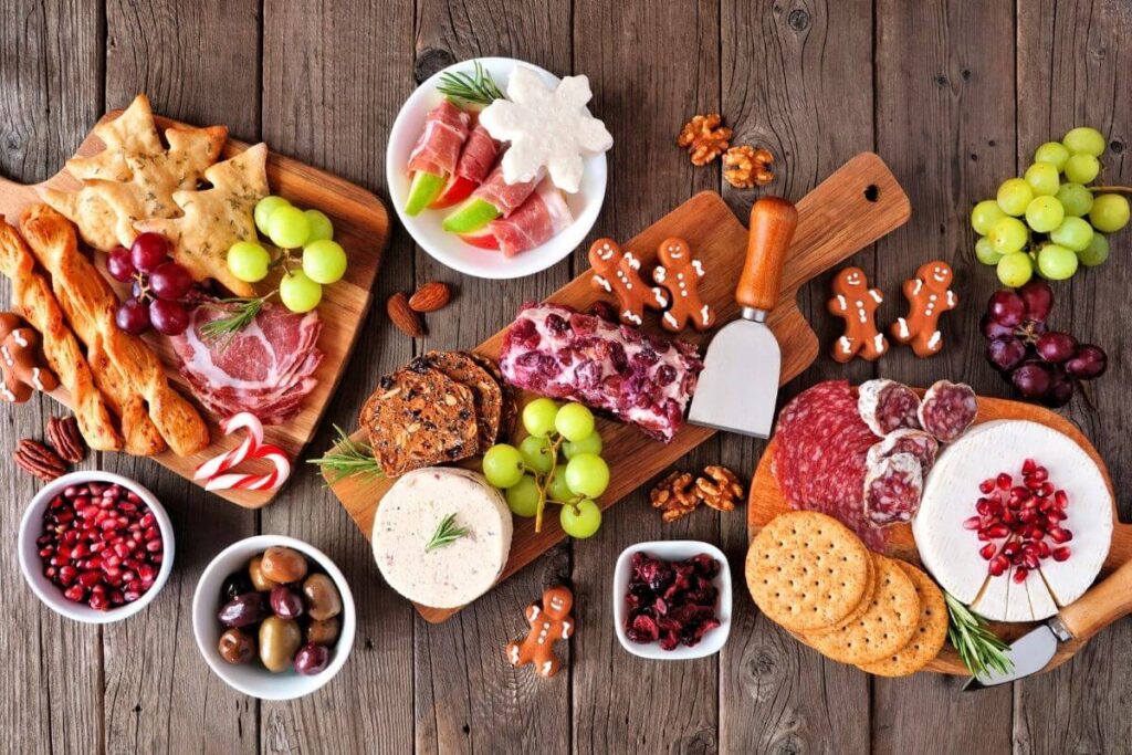 christmas themed charcuterie board with gingerbread men snowflakes cranberries grapes green sprigs laid out nicely on a board