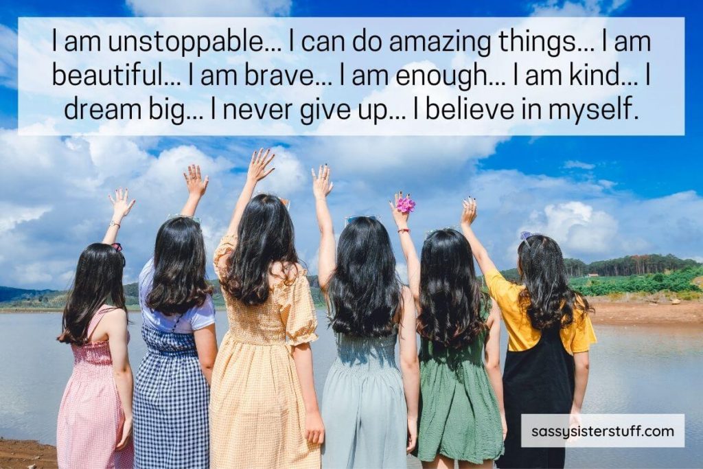 empowering words for women written at the top of an image of six young girls standing on a shoreline with their left hands raised in the air like they are empowered