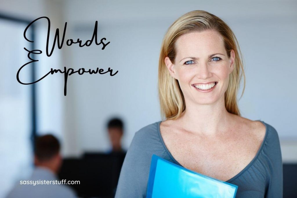 confident blonde woman in a blue shirt in an office smiles at the camera feeling empowered