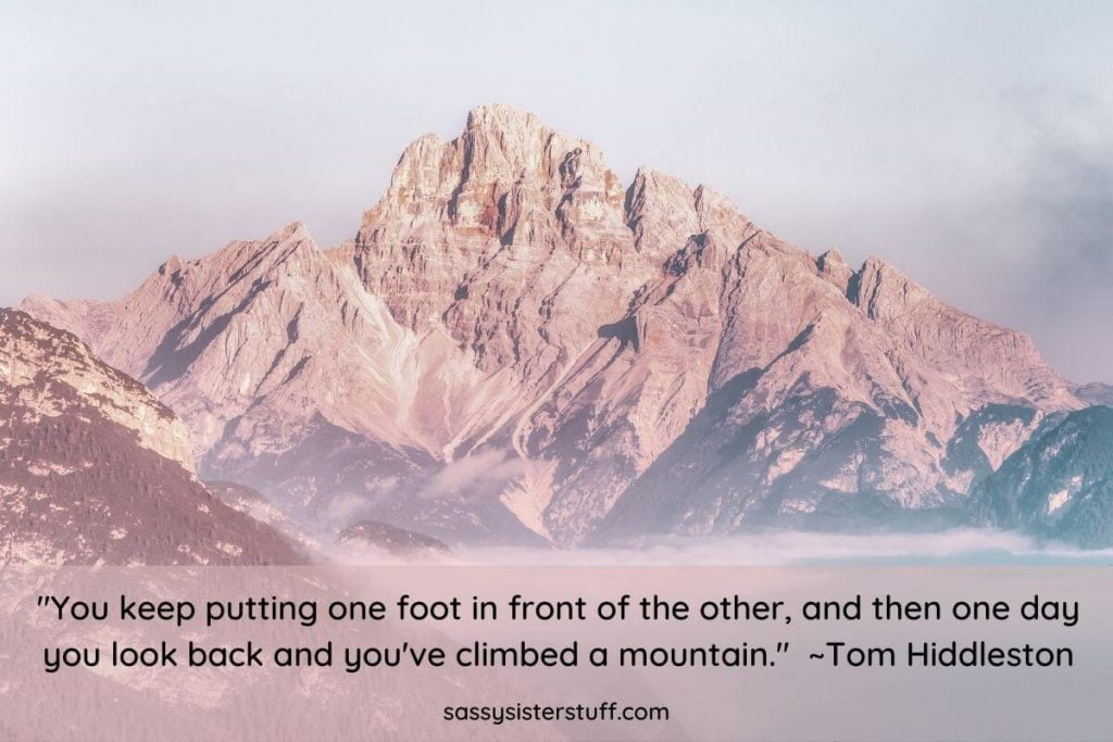 rocky mountains against a cloudy sky with an inspirational quote about putting one foot in front of the other