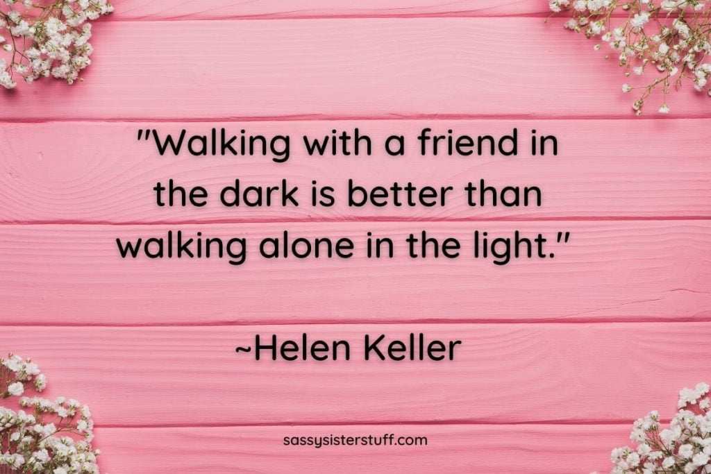 Helen Keller quote about walking with a friend on a pink background with babys breath flowers in each corner