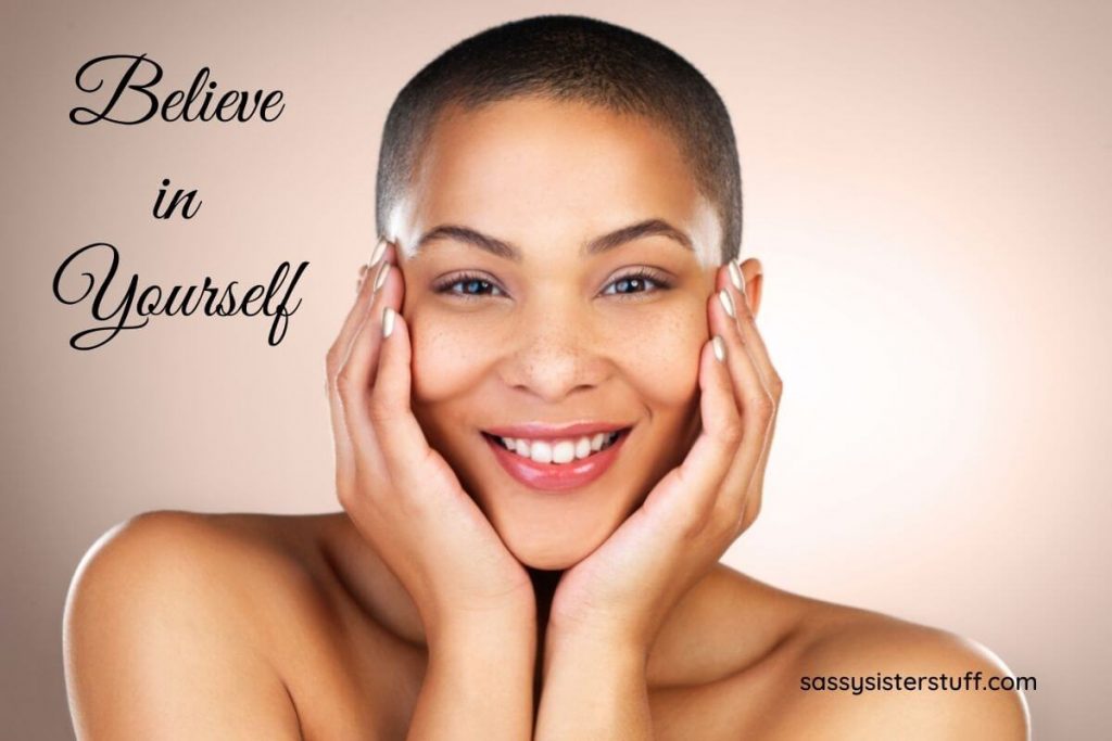 A beautiful woman smiles directly at the camera with her hands on her cheeks suggesting that she has a healthy mindset and believes in herself