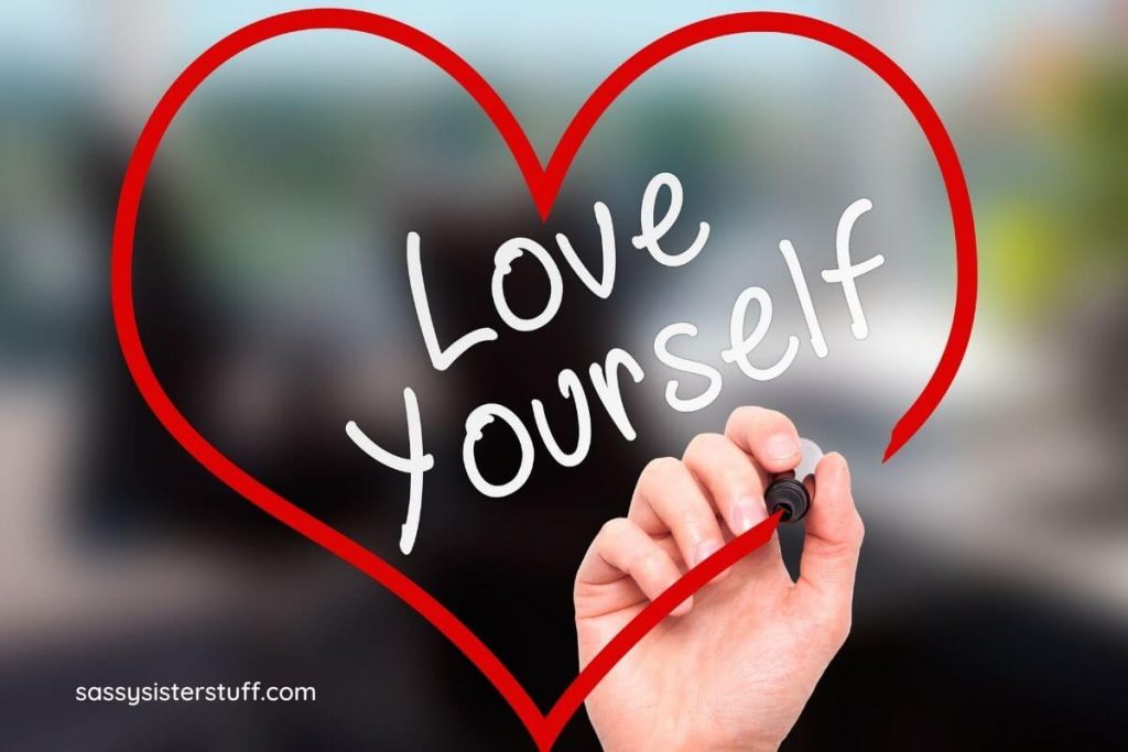 a woman's hand draws a red heart around words that say love yourself