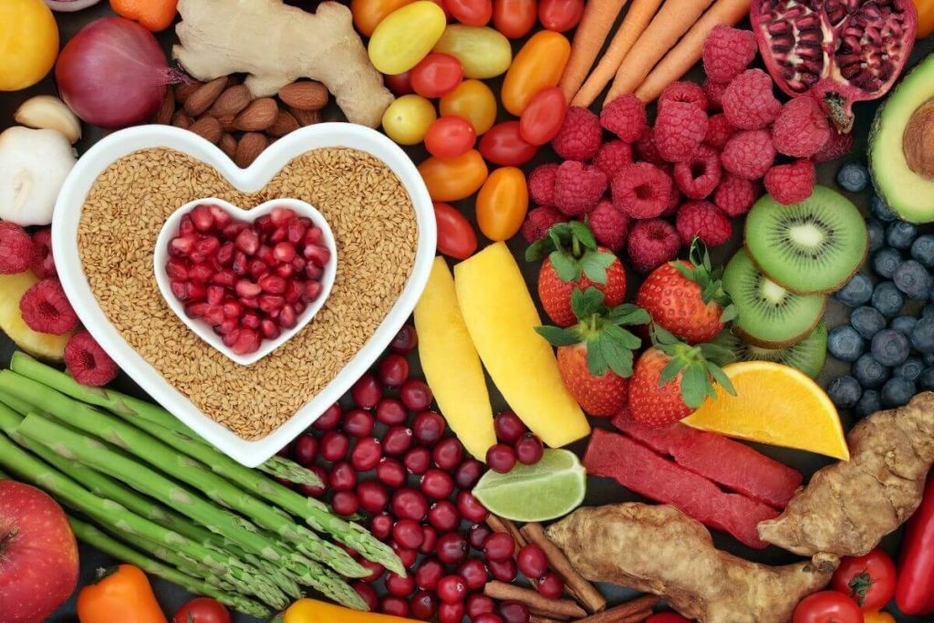 a brightly colored photo of beautiful and healthy fresh foods like raspberries kiwi sesame seeds blueberries carrots apples and others pomegranates