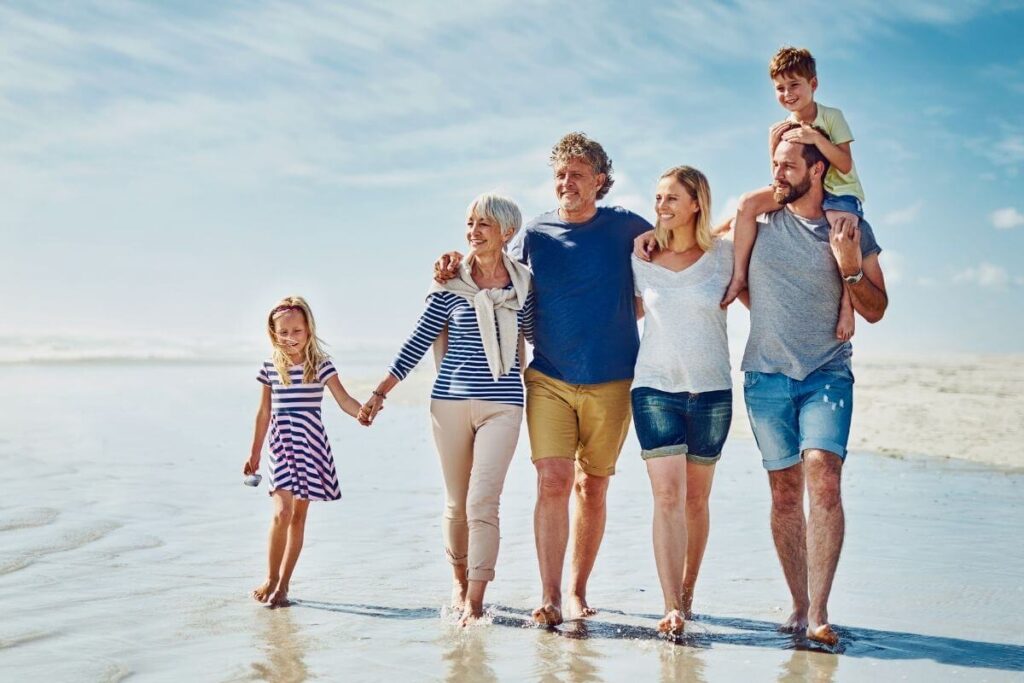 a multi-generational family with parents grandparents and kids walk along a beach showing how to live your best life