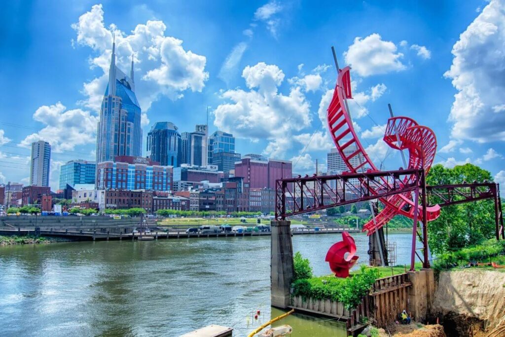 a colorful photo of the cityscape of nashville along the river with the blue sky in the background