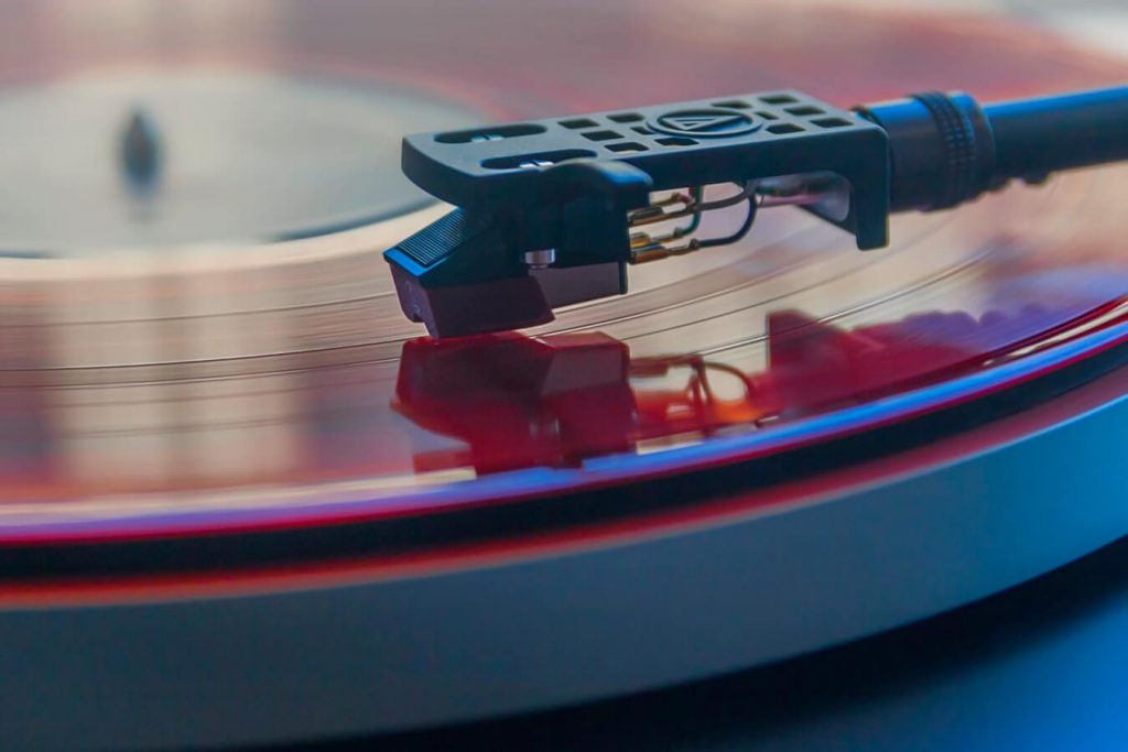 close up image of an old fashioned turn table play a red vinyl album